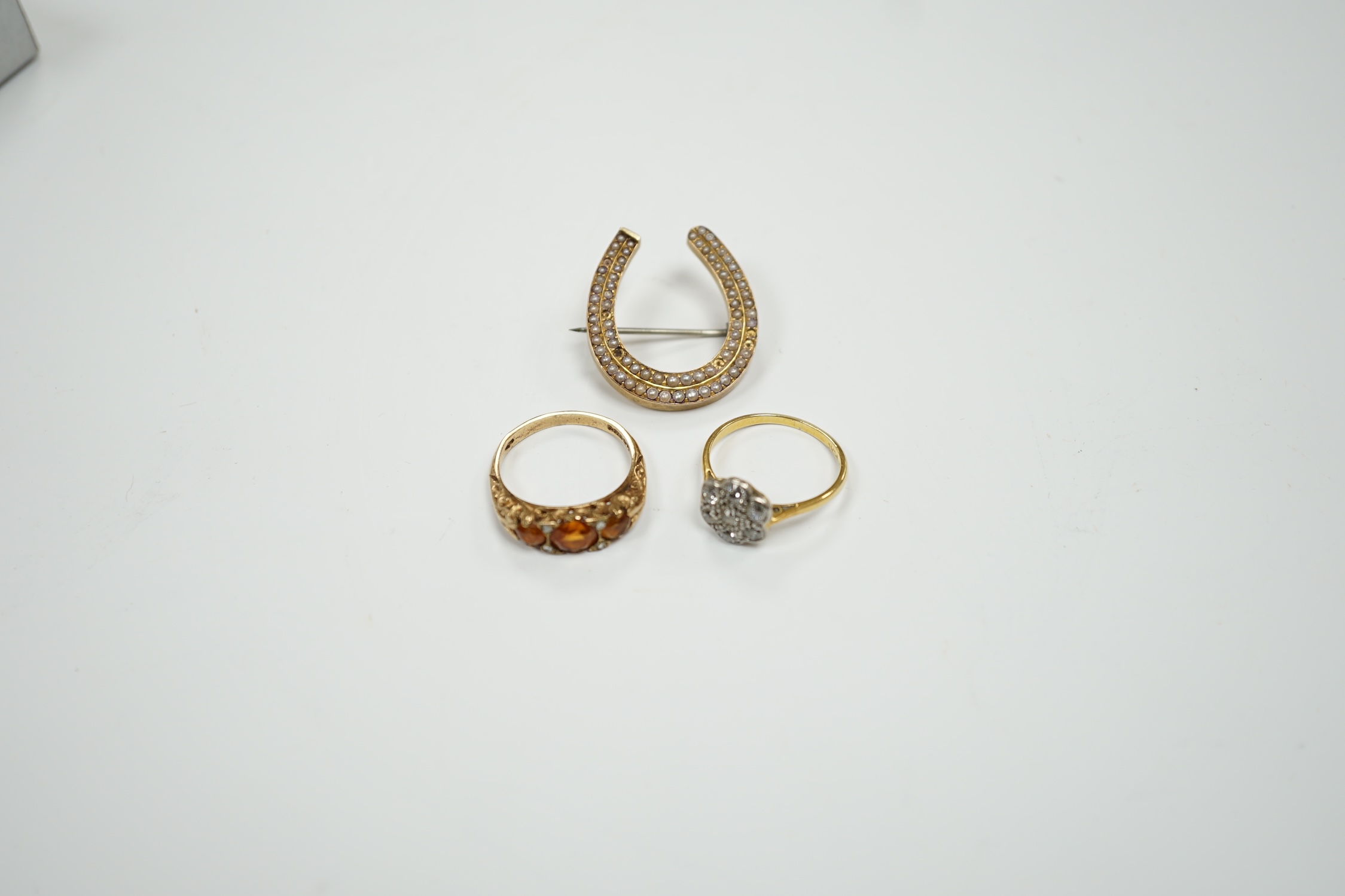 A 1920's 18ct, plat and millegrain set diamond flower head cluster ring, size L/M, a later 9ct gold and three stone citrine ring, with rose cut diamond chip spacers and a yellow metal seed pearl cluster set horseshoe bro